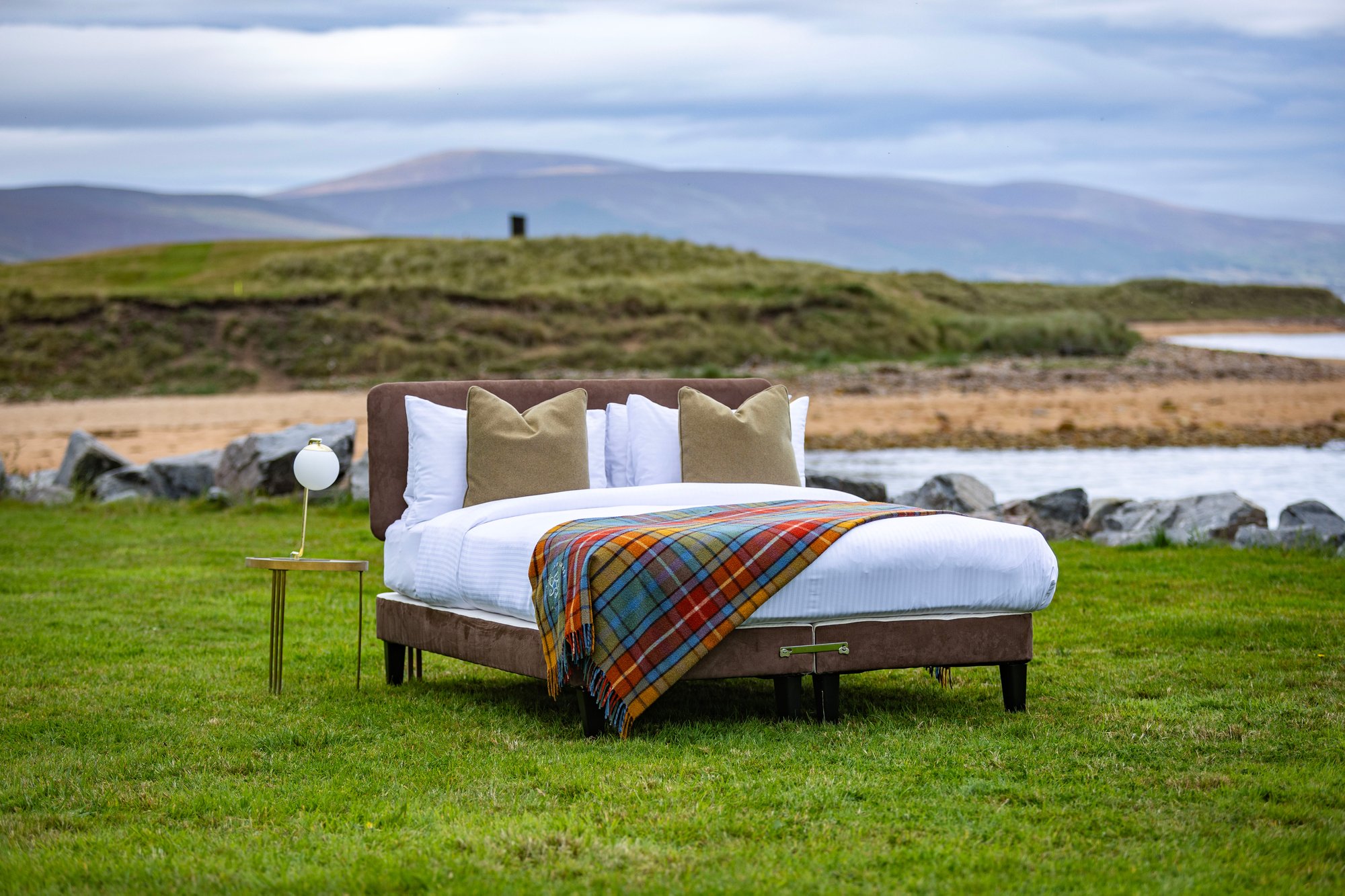 A chocolate bed base and headboard on a grassy ledge by the beach